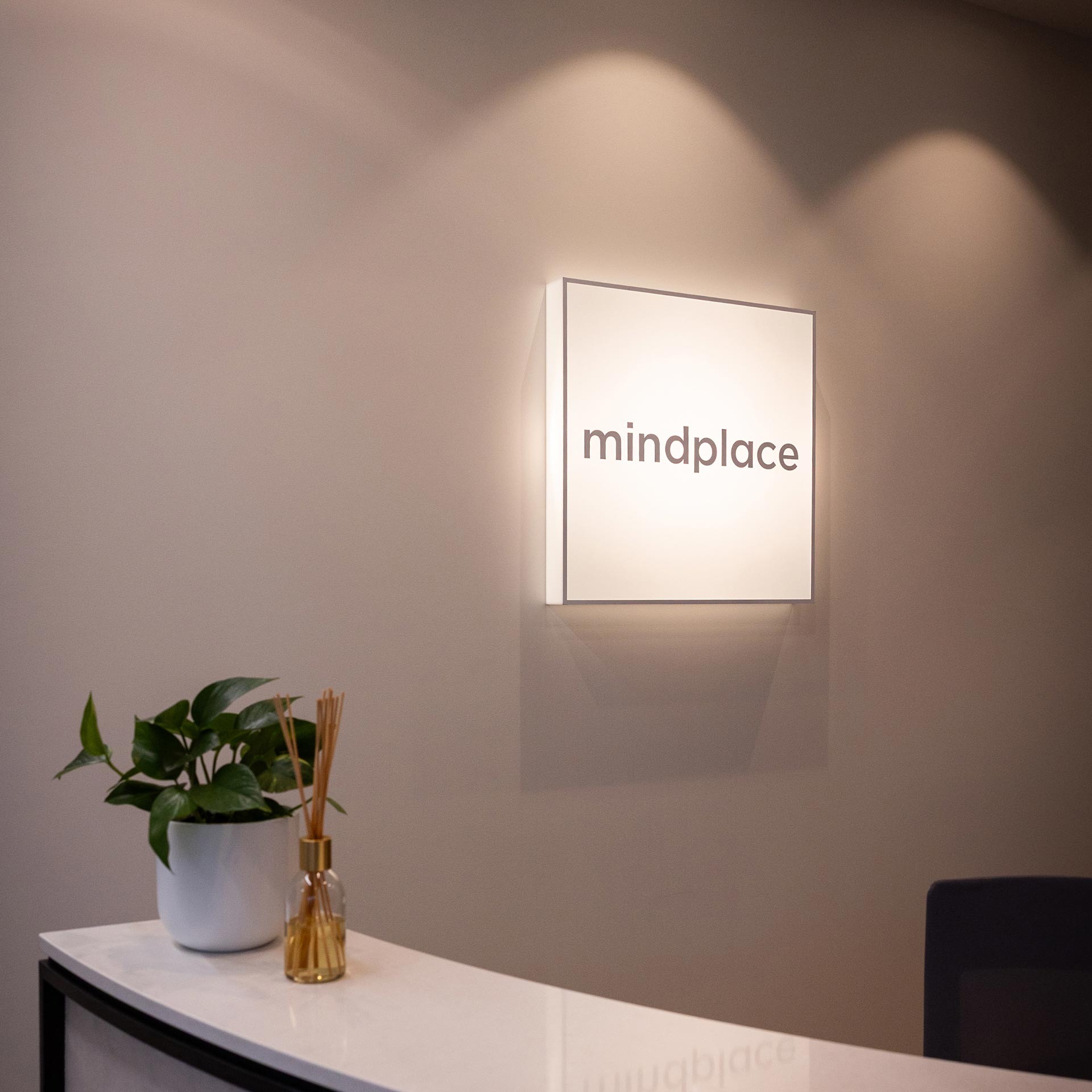 Mindplace reception sign on a softly lit clinic wall above a reception desk
